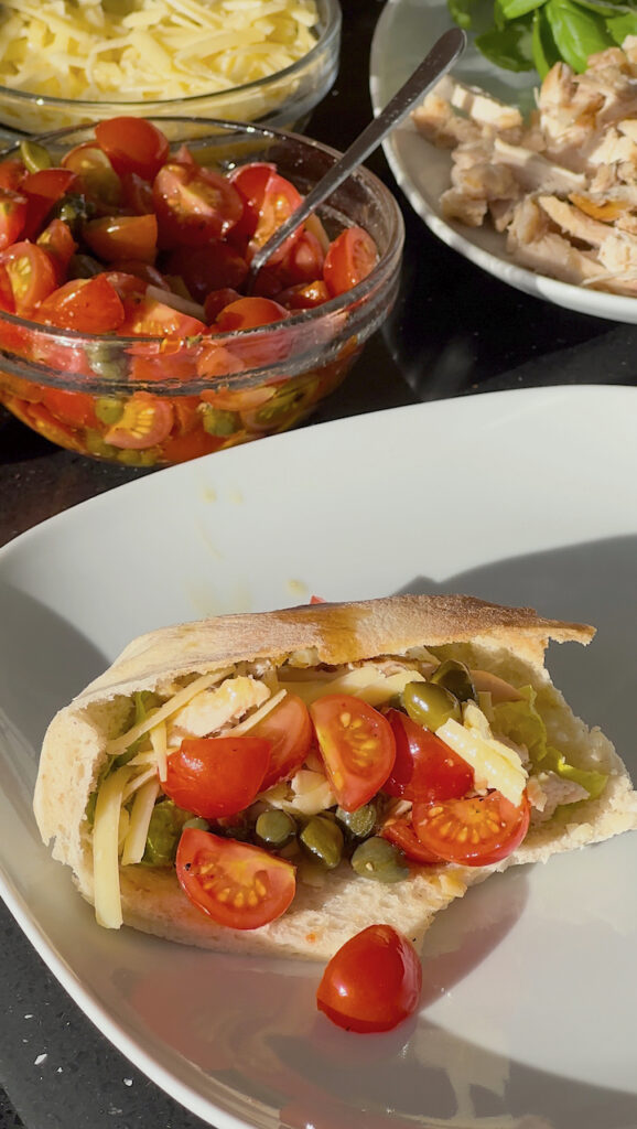 Sourdough pita pocket filled with grilled chicken, salad, cheese, tomatoes and capers